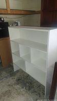 White laminate bookcase showing front and side views with multiple shelving compartments