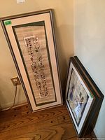 Three framed Egyptian papyrus prints leaning against wall, showing frames and partial images