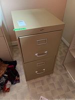 Front view of beige two drawer metal file cabinet with label holders and pull handles on drawers.