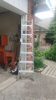 Front view of the aluminum Lite ladder model 856 step ladder standing outside a garage near a brick wall showing its height and overall condition.