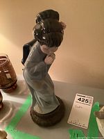 Porcelain figurine of a Japanese Geisha named Sayonara by Lladro, showing front and side views with detailed features and base.