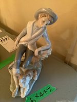Front angle view of the Lladro porcelain figurine showing the boy sitting and the dog at his feet.