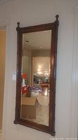 Full view of the framed mirror hanging on a wall with home interior background visible.