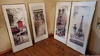 All four framed prints leaning against a wall, arranged side-by-side showing full images and frames