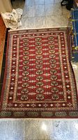 Full view of the red Oriental-style rug showing the repeating medallion pattern and the overall wear condition.