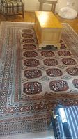 Photo showing the full rectangular wool blend rug with coffee table placed on top and chairs surrounding, highlighting the design and colors of the rug.