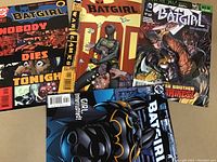 Photo showing four Batgirl comics from DC Comics, each with distinct cover art highlighting Batgirl in action, labeled as high-grade by seller.