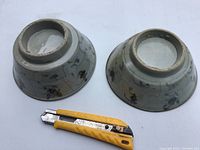 Pair of unmarked antique glazed pottery bowls shown upside down next to a utility knife for scale.