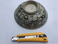 Bottom of the pottery bowl with unmarked base and black geometric and scroll patterns