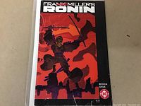 Front cover of Frank Miller's Ronin #1 comic book showing the main character with sword in a red and black stylized background. DC Comics logo and price $2.50 visible.