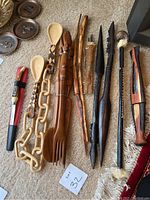 Overhead view of collection of African wooden serving utensils and decorative carved wood pieces laid on carpet