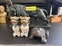 Overall group shot: pair of ceramic Foo Dogs at front left, bronze lion sculpture behind, cast iron frog at front right.