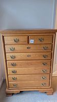 Front view of a solid wood chest of drawers showing seven large drawers and two smaller top drawers with brass handles.