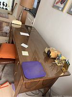 Side view of walnut-finish wooden desk with glass top protector and drawers