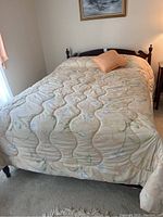 Full size bed covered with a comforter and an orange pillow, showing the bed ready for use.