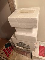 Stacked white styrofoam packaging for Hawthorne Village items with boxes underneath.