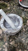 Marble mortar and pestle on green veined stone surface.