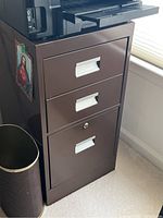 Photo of 3-drawer file cabinet and trash bin side by side