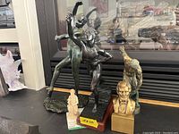 Photo showing two ballet dancer statues, bronzed male figure, and Abraham Lincoln bust on table in front of fireplace.