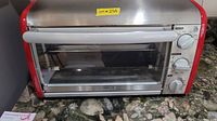 Front view of the red and gray toaster oven showing the door, handle, and control knobs.
