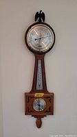 Full view of wooden wall clock showing clock face, temperature gauge, humidity gauge, and wood design.