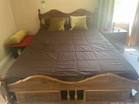 Full view of queen bed frame with brown-covered mattress and pillows