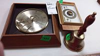 Photo showing the large square barometer with three dials and the smaller rectangular barometer/thermometer alongside the brass school bell.