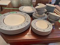 Group shot of stacked dinnerware, cups, saucers, and finger bowls on table