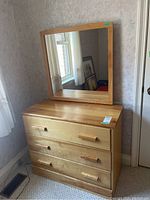 Front view of the wood dresser with three drawers, showing the attached matching rectangular mirror on top.