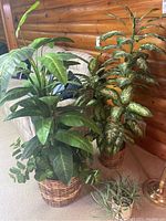 Two large faux plants in wicker baskets with detailed view of leaves and baskets.