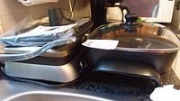 Photo showing both grills side by side on a kitchen counter, one silver and black 4-in-1 GE grill and one black GE grill with glass lid.