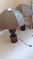 Pair of lamps with dome-shaped fabric shades and wooden bases shown side by side on carpet.