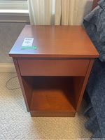 Front view of one side table showing drawer and open cubby storage space.