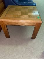 Full view of one wood side table showing checkered parquet pattern on top and four sturdy legs.