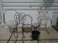 Front view of all 5 items: 2 large wire basket planters with handles and 3 chair-shaped plant stands with intricate metal scroll designs in black and gold finishes.