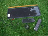 All three solar panels with visible wiring and clips placed on grass with a measuring stick showing largest panel size approximately 14 inches by 5 inches.