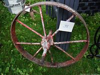 Top view of antique steel wheel showing red paint, rust, and eight spokes with central hub.