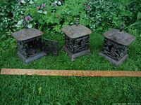 Three lanterns side by side on grass next to a ruler