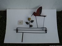 Full view of vintage steel whirlygig featuring a stylized bird and flower on metal frame.