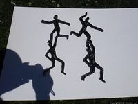 Two black cast aluminum abstract human figures in dynamic athletic poses placed on white background outdoors with some grass visible. Figures are approximately 15 inches tall.