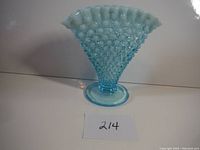 Full frontal view of blue hobnail glass vase showing ruffled white top edge, flared shape, and round base.