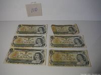 Top view of six vintage Canadian one dollar bank notes, with one showing major damage and wear.