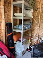 Two beige plastic shelving units with five shelves each, some shelves holding pillows and items, in a wooden framed room.