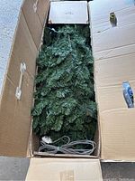Open box showing artificial pine branches with pre-lit LED string lights inside and an electrical cord.