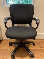 Front view of black HON office task chair showing padded seat and backrest with armrests and caster wheels