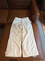 Full view of white B by Burton snowboard pants laid flat to show overall condition and design