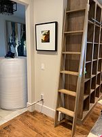 Photo showing full wooden ladder leaning against wall with framed artwork nearby, illustrating height and style.