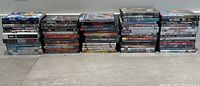 Wide shot of stacked DVDs in cases showing spines and some front covers to identify several titles.