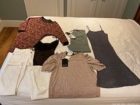 Full view of the clothing items laid out on the bed in good condition, some with tags