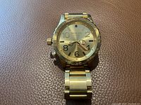 Front view of the Nixon men's watch showing the sunray gold dial with Arabic numerals and rotating bezel.